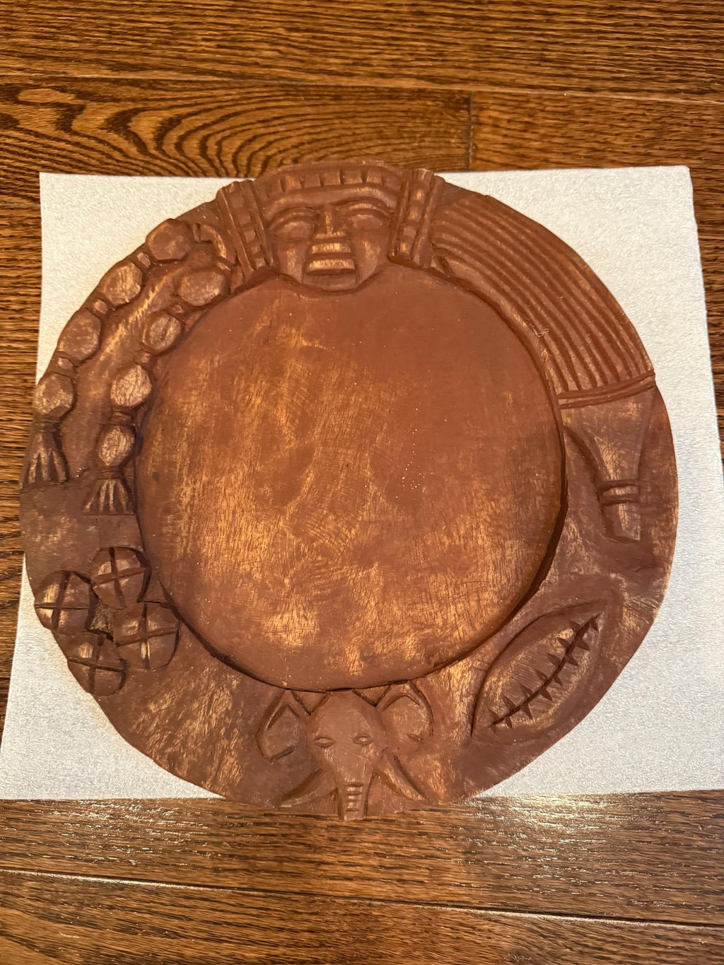 Wooden decorative plate with carvings on a wooden surface
